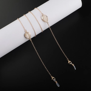 Close-up of golden eyewear chain with white shell leaf charms and silicone loops