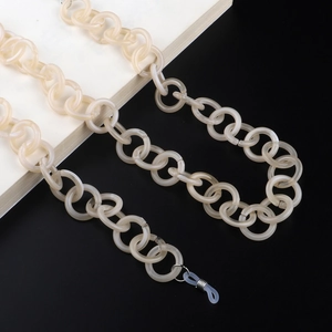 Détail de chaîne à lunettes en acrylique crème avec anneaux argentés et embouts en silicone