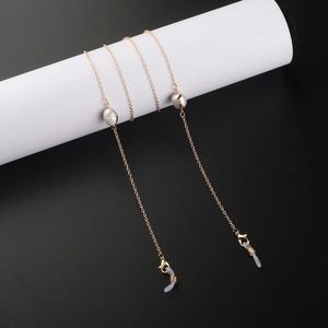 Chaîne de lunettes dorée élégante avec perles blanches sur fond noir minimaliste