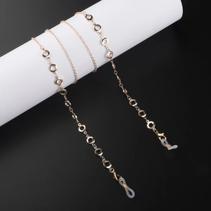 Elegant gold metal glasses chain with circular charms on a minimalist display