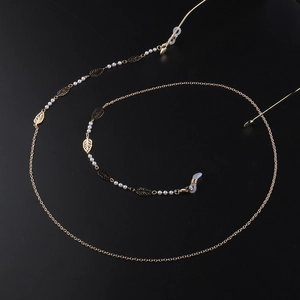 Élégante chaîne de lunettes dorée avec feuilles évidées et perles sur fond noir