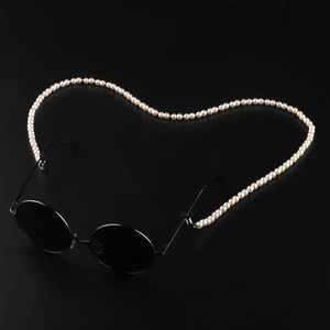 Round black sunglasses with heart-shaped faux pearl eyewear chain on dark background