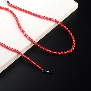 Macro detail of red faux pearl eyeglass chain with gold beads and rubber connectors