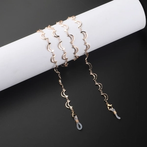 Gold moon charm eyeglass chain with lobster clasps and silicone loops on a white platform
