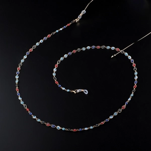Golden eyewear chain with colorful evil eye beads and lobster clasps on black background