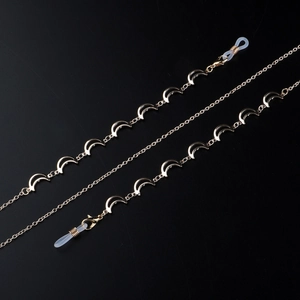 Chaîne de lunettes dorée avec breloques lune polies et boucles silicone sur fond noir