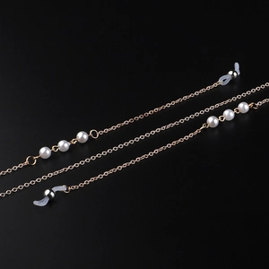 Elegante goldene Brillenkette und Maskenband mit weißen Perlen auf schwarzem Hintergrund