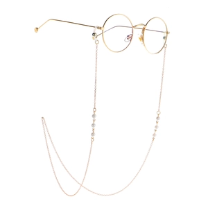 Elegante goldene Rundbrille mit passender Perlen-Metallkette auf weißem Hintergrund