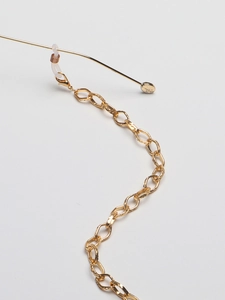 Macro detail of gold oval eyewear chain with lobster clasp and silicone loop connectors