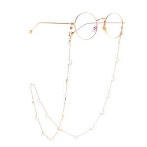 Round gold metal glasses with moon charms chain accessory on white background