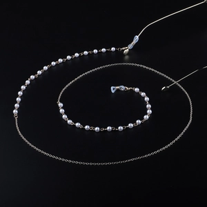 Chaîne à lunettes dorée élégante avec perles blanches et boucles silicone sur fond noir