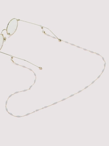 Detail of gold chain sunglasses strap featuring light blue pearls and silicone loops