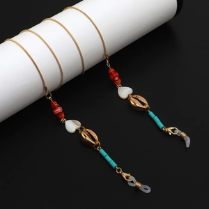 Gold snake chain eyewear strap with shell charms and turquoise beads on white stand