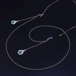 Chaîne lunettes dorée avec pendentifs chat noir et bateau sur fond bleu foncé