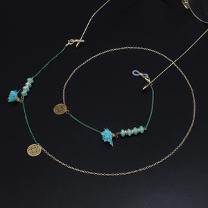 Détail d'une chaîne à lunettes bohème avec fleurs en tissu turquoise et breloques