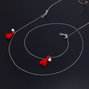 Chaîne de lunettes en métal argenté avec glands rouges et perles blanches sur fond noir