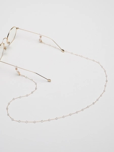 Detail of minimalist eyewear chain with gold links and clear beads on glasses