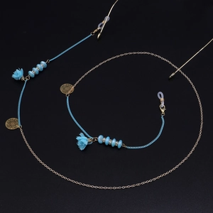 Détail de perles de fleurs en verre bleu et chaîne dorée à pompons pour lunettes