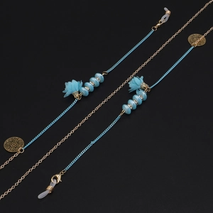 Détail de perles de fleurs en verre bleu et glands sur une chaîne de lunettes à la main