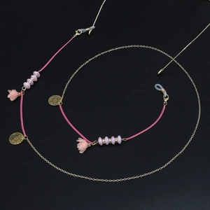 Détail de perles roses en acrylique et glands de fleurs en tissu sur chaîne à lunettes