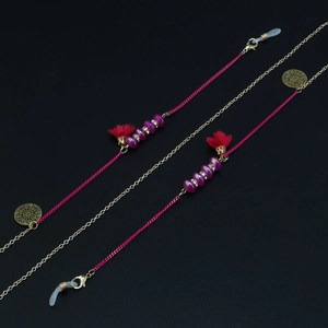 Détail de chaîne à lunettes bohème avec perles violettes, pompons rouges et breloques