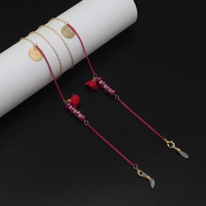 Détail d'une chaîne à lunettes perlée rose rouge avec breloques dorées et pompon