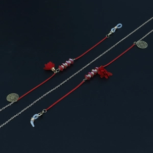 Détail de la chaîne de lunettes rouge avec gland doré et breloques florales en métal