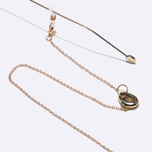 Détail d'une chaîne de lunettes dorée avec pendentifs coquillages et boucles en silicone