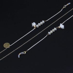 Détail de chaîne de lunettes avec perles fleurs en verre, gland doré et fermoir mousqueton