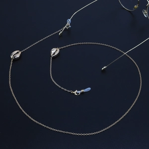 Chaîne de lunettes minimaliste dorée avec pendentifs coquillages sur fond bleu