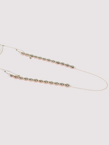 Detail of gold seashell eyeglass chain featuring metallic cowrie shells and clear hooks
