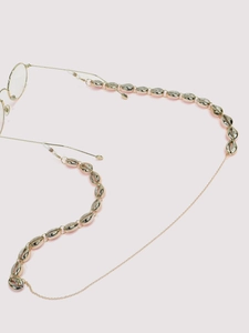 Detailed view of golden eyewear chain featuring textured shell beads and silicone loops