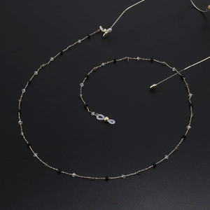 Chaîne de lunettes dorée tendance avec perles en cristal sur fond noir