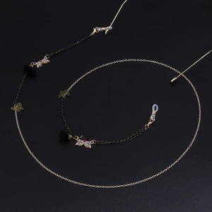 Détail d'une chaîne de lunettes papillon colorée avec glands noirs sur fond mat