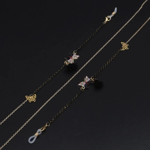 Détail de chaînes de lunettes avec papillons en émail, breloques et pompons noirs