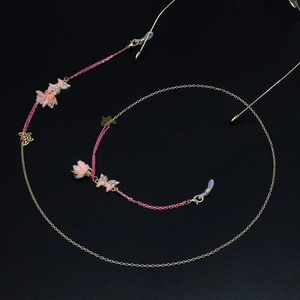 Détail d'une chaîne de lunettes avec fleurs roses, papillons et maille dorée chic