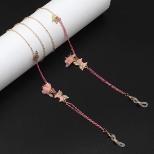 Détail de la fleur en mousseline rose et des papillons sur la chaîne de lunettes dorée