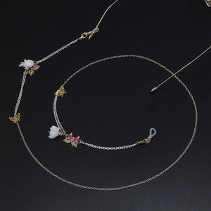Vue détaillée d'une chaîne de lunettes dorée avec papillons colorés et fleurs blanches