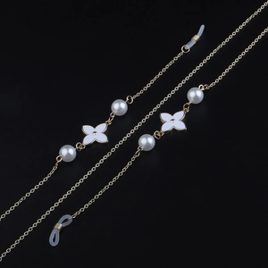 Elegant gold metal eyewear chain with white enamel flowers and pearls on black background