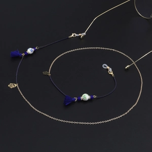 Detail of blue ceramic beads, tassels and gold floral charms on eyewear chain