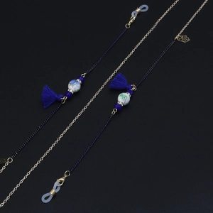 Detail of colorful ceramic beads and navy blue tassels on gold metal eyewear chain