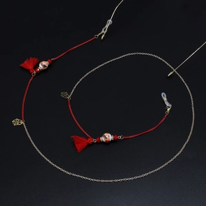 Detail of red tassel and ceramic bead on handmade braided glasses chain with gold link