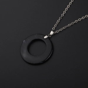 Minimalist silver chain necklace with a smooth black circular obsidian-style pendant
