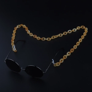 Detail of amber tortoiseshell acrylic eyewear chain on retro black sunglasses