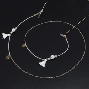 Detail of colorful ceramic beads and cotton tassels on a gold glasses chain