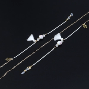 Detail of a handmade eyeglass chain with white tassels, floral beads and golden accents
