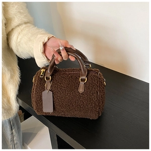 Dettaglio borsa Boston in sherpa marrone con manici in pelle e fibbie dorate
