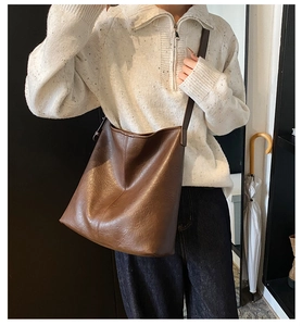 Detail of dark brown leather tote bag featuring a textured finish and slender shoulder strap