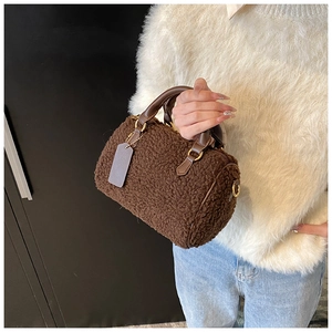 Detail of dark brown plush barrel bag with faux lamb fur texture and leather handle