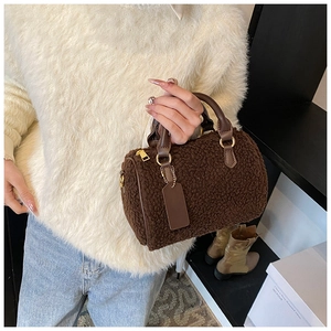 Close-up of plush brown Boston bag with smooth leather handles and gold metal zipper